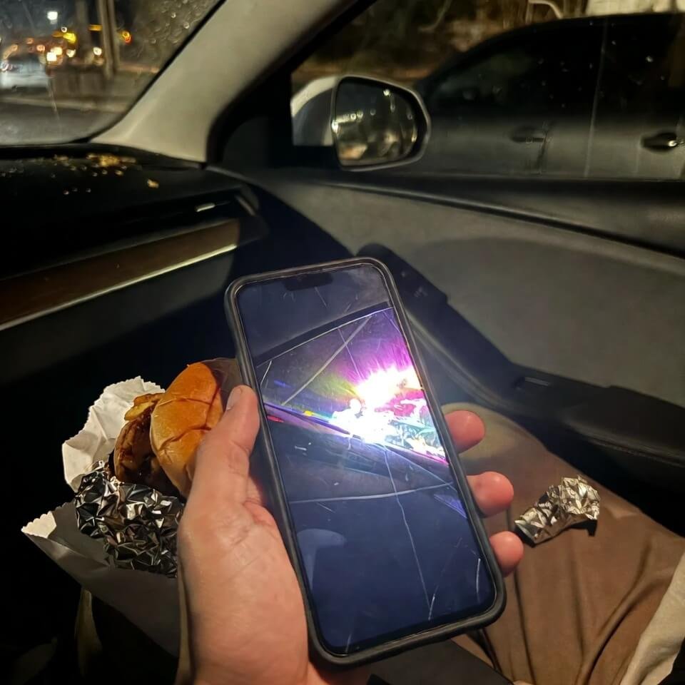 Embarrassed guy holding shattered iPhone at drive-thru window
